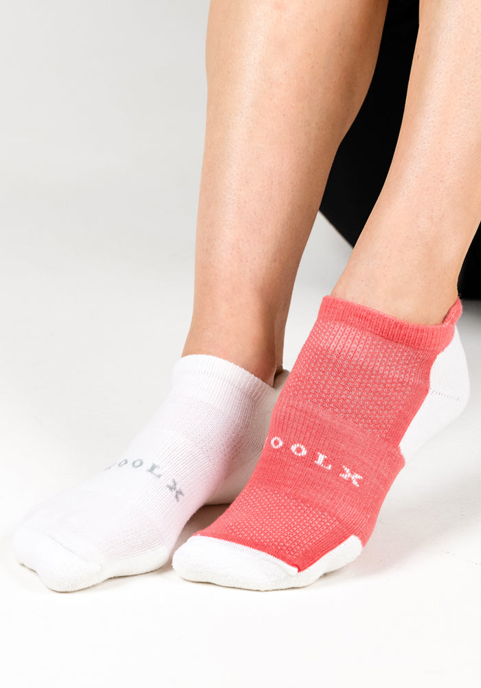Two feet wear mismatched Woolx Womens Rowan No Show Socks – White Lightning: the left is white with gray text, and the right is red with white text. Background is plain white.