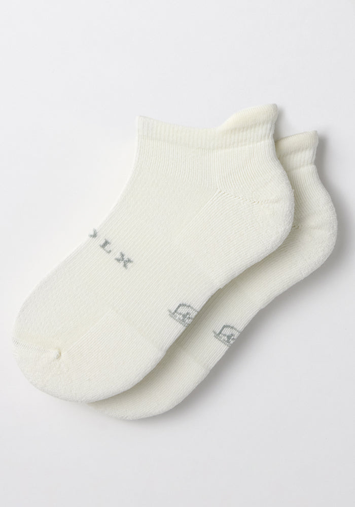 The Woolx Womens Rowan No Show Socks in White Lightning feature cushioned ankle support and subtle gray sole lettering, shown overlapping on a plain white background.